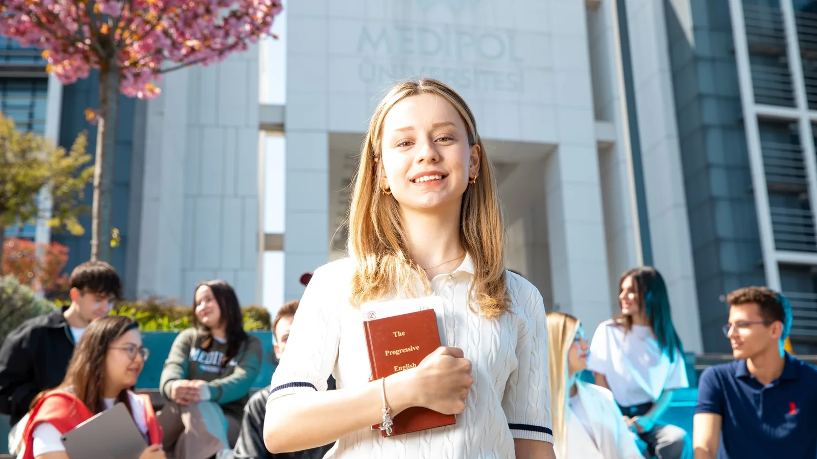 A university learner holding books on a busy campus